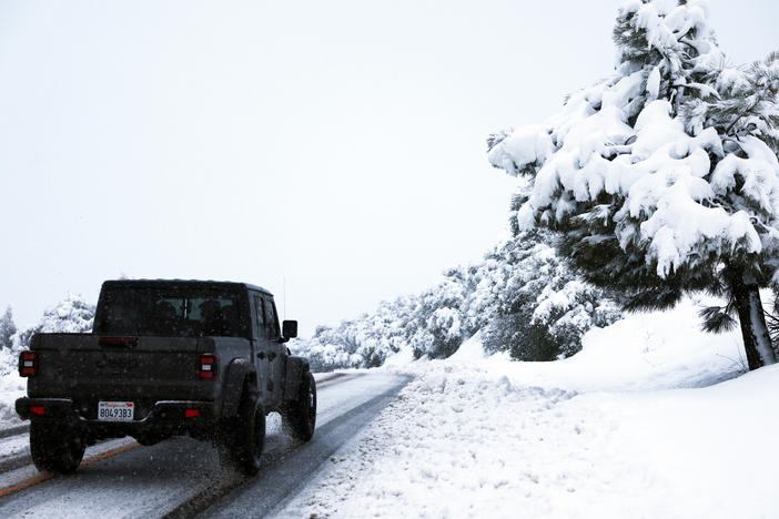 A person drives along a snowy roadway in Los Angeles County, in the Sierra Pelona Mountains, on Saturday near Green Valley, Calif. A major storm delivered heavy snowfall to the mountains with some snow reaching lower elevations in Los Angeles County. More is expected on Tuesday into Wednesday.
