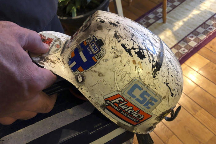 Retired coal miner John Robinson, who suffers from black lung disease, displays his mining helmet at his home in Coeburn, Va., in 2019.