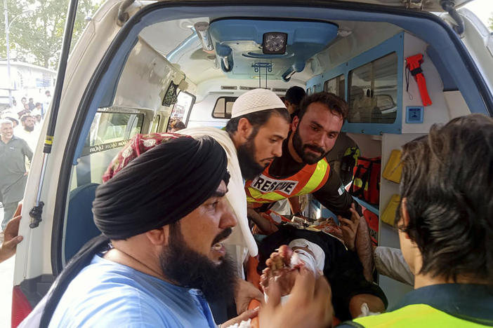 In this photo provided by Rescue 1122 Head Quarters, rescue workers carry a wounded man after a bomb explosion in the Bajur district of Khyber Pakhtunkhwa, Pakistan on Sunday.