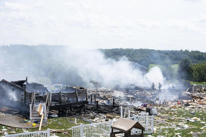 Two firefighters stand on the debris around the smoldering wreckage of the the three houses that exploded near Rustic Ridge Drive and Brookside Drive in Plum, Pa., on Saturday.