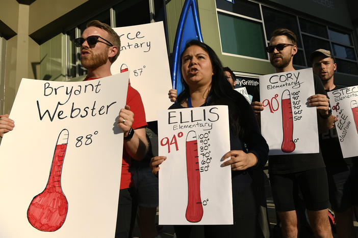 Protesters hold up signs outside of the Denver Public Schools administration building to demand equity for students attending classes in excessively hot classrooms.