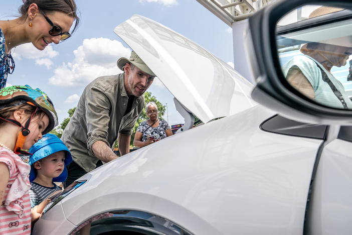 A family inspects the engine of a new Toyota Prius model during the Electrify Expo In D.C. in Washington, D.C., on July 23, 2023. Getting an electric vehicle tax credit of up to $7,500 will get a lot easier next year.
