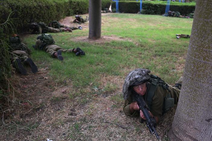 Israeli soldiers are shown taking cover in Sderot on Monday, Oct. 9, 2023, during a rocket attack from the Gaza Strip.