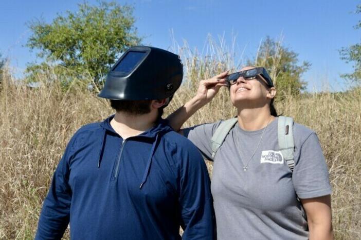 Jonathan Quirarte, left, watched the eclipse with his girlfriend at Phil Hardberger Park in San Antonio. To protect his eyes, Quirarte wore a welder mask he purchased for a previous eclipse.