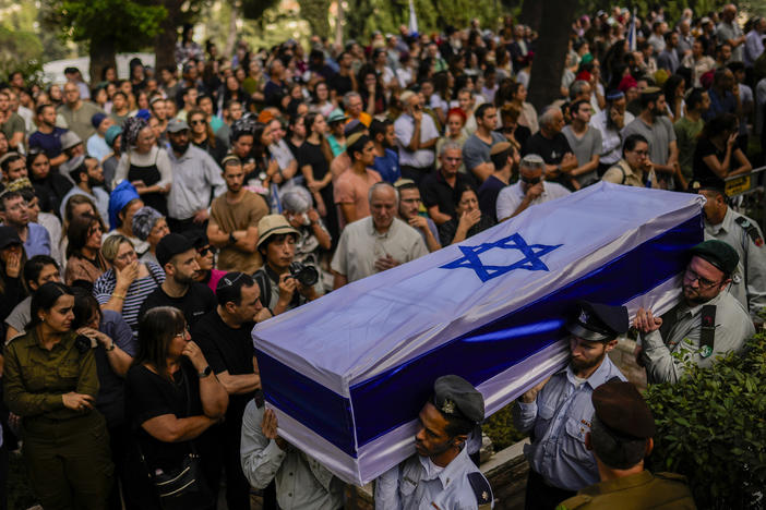 Israeli soldiers carry the flag-covered coffin of a person killed in the Hamas attack earlier this month. Rabbis and reservists have worked around the clock at a military base in Israel to identify and count the dead.