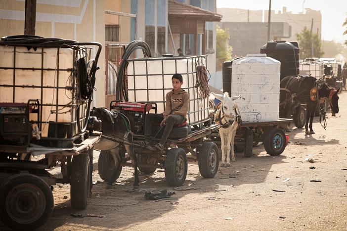 A boy in Khan Younis sits on donkey-drawn cart loaded with a water tank, as drinking water and fuel become increasingly scarce in Gaza.
