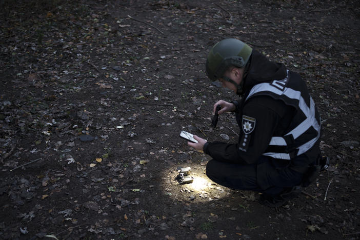 A Ukrainian police officer uses a flashlight to search for drone debris near the site of an explosion following a Russian drone attack in Kyiv, Ukraine, on Saturday, Nov. 25, 2023, its most intense on the Ukrainian capital since the beginning of its invasion, military officials said.