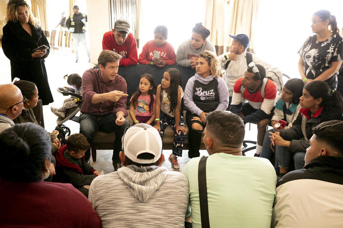 Denver Mayor Mike Johnston speaks with a group of migrants, many of whom are living outside, in a hotel run by the city. Nov. 18, 2023.