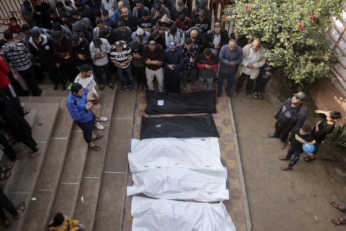 Palestinians pray near the wrapped bodies of relatives killed in the Israeli bombardment of the Gaza Strip, outside a morgue in Khan Younis on Wednesday.