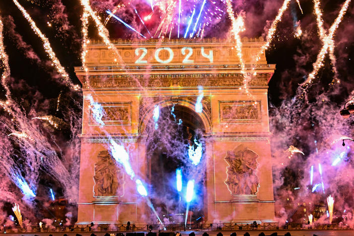 Fireworks explode next to the Arc de Triomphe with "2024" projected at the Avenue des Champs-Elysees during New Year celebrations in Paris, early on January 1, 2024.