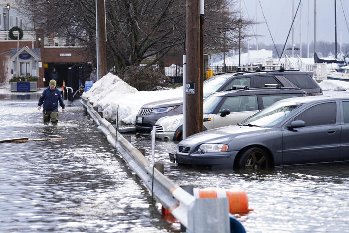 A man wades through a flooded parking lot near Widgery Wharf on Wednesday in Portland, Maine.