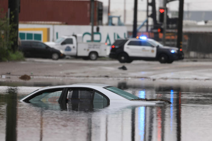 A car sits partially submerged on a flooded road during a rain storm in Long Beach, Calif., on Thursday.