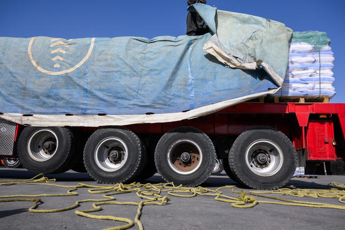 An Egyptian truck driver removes a tarp covering humanitarian aid before it is inspected on its way to the Gaza Strip at the Kerem Shalom Crossing in Israel on Dec. 22, 2023.