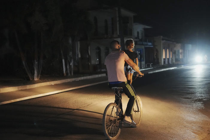 A a man pedals carrying a girl during a scheduled power outage in Bauta, Cuba, Monday, March 18. The island is facing an energy crisis, with waves of blackouts worsening in recent weeks.