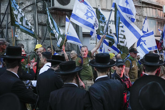 Members of the 'Brothers in Arms' reservist protest group wave Israeli flags during a demonstration in the ultra-Orthodox neighborhood of Mea Shearim, demanding equality in Israel's military service, in Jerusalem on Sunday, March 31, 2024.