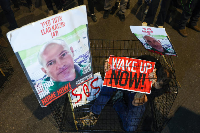 A man sits in a cage with portraits of 47-year-old Israeli hostage Elad Katzir as relatives and supporters of Israeli hostages stage a demonstration in Tel Aviv on March 26.