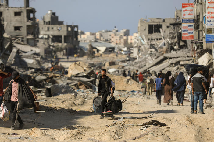 People walk past destroyed buildings along a road in Khan Younis on April 7, 2024 after Israel pulled its ground forces out of the southern Gaza Strip, six months into the war sparked by the Oct. 7 attacks.