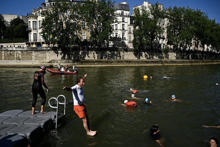 People jump into the Seine River in Paris on July 17, after Mayor Anne Hidalgo swam in the river to demonstrate that it is clean enough to host the outdoor swimming events at the Paris Olympics later this month.