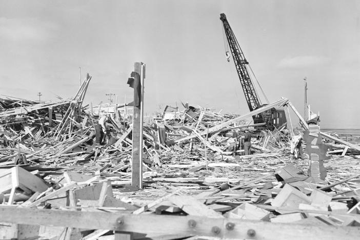 Workmen searched through the debris of what was the carpenter shop on the pier at Port  in Chicago, Calif. on July 18, 1944 after the building was leveled by the explosion of two munition ships the evening of July 17. Other buildings on the waterfront and in the town itself were shattered by the terrific blast, which was felt 50 miles from the scene. 