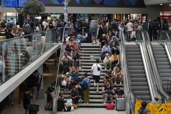 Travelers sit on stairs at the Gare de Montparnasse at the 2024 Summer Olympics on Friday in Paris. Hours away from the opening ceremony of the Olympics, high-speed rail traffic to the French capital was severely disrupted on Friday following what officials described as "criminal actions" and sabotage.
