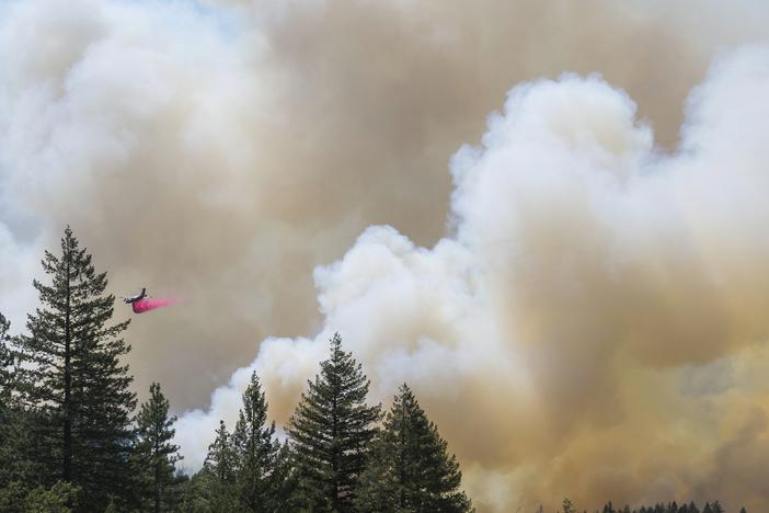 A plane drops fire retardant on the Park Fire near Forest Ranch, Calif., Sunday, July 28, 2024. Smoke from the fire is causing air quality issues across the Northwest and parts of Canada.