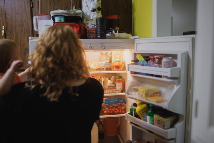 Annalise and Ellie Currence stand at the fridge deciding on dinner at their home in Belton, Mo., on July 17.