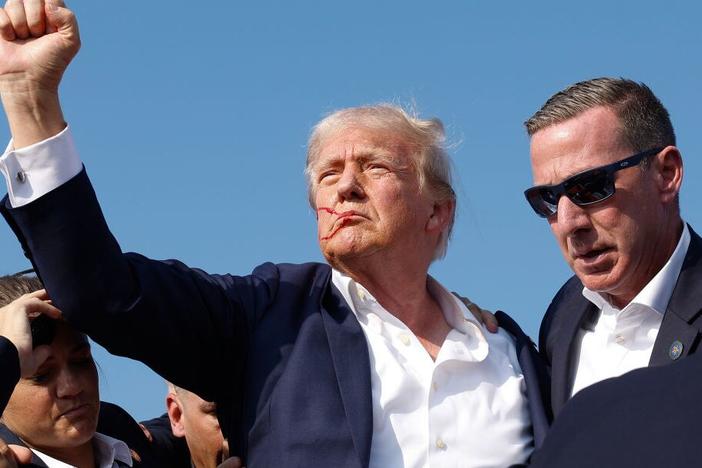 Former President Trump pumps his fist as he is rushed offstage during a rally on July 13, 2024, in Butler, Pa.