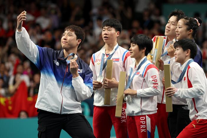 Lim Jong-hoon of South Korea takes a selfie with North Korean silver medalists Kim Kum-yong and Ri Jong-sik, center, with Chinese gold medalists Wang Chuqin and Sun Yingsha flanking South Korean Shin Yu-bin.