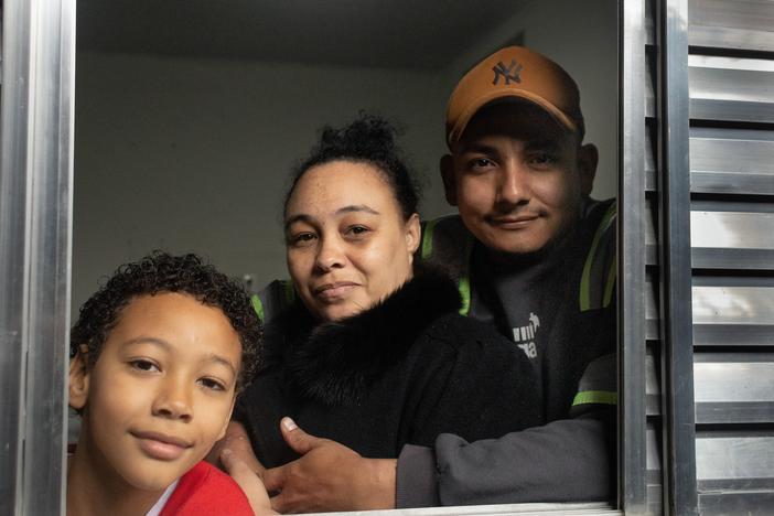 Erica Lacerda de Souza, son Henrique and husband Bruce Lee de Souza, relax in their new home in Guaianazes, São Paulo. The family lost their home when the pandemic took away their livelihoods. They moved in about two months ago after being homeless, then getting a tiny transitional residence/