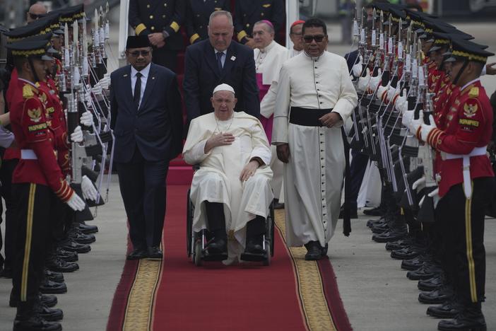 Pope Francis, seated in his wheelchair is welcomed as Indonesian Minister of Religious Affairs Yaqut Cholil Qoumas, center left, walks during an official welcoming ceremony at Soekarno-Hatta International Airport in Tangerang on the outskirts of Jakarta, Indonesia, Tuesday, Sept. 3, 2024.