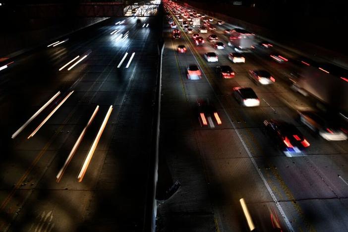 In a long exposure image, cars and trucks drive on the 405 Freeway during Los Angeles rush hour traffic in March 2022.