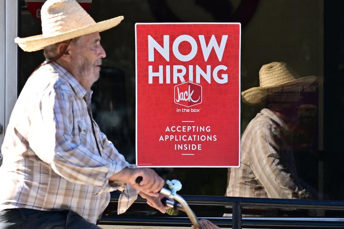 A cyclist rides past a "Now Hiring" sign posted on a business storefront in San Gabriel, Calif., on Aug. 21, 2024. U.S. employers added 142,000 jobs in August, while the unemployment rate dipped to 4.2%.