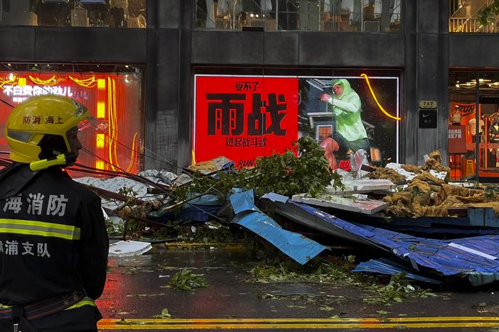 A firefighter stands near debris along a business street in the aftermath of Typhoon Bebinca in Shanghai, China on Monday.