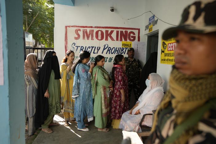 Paramilitary soldiers stand guard as people queue up to vote during the first phase of the Jammu and Kashmir assembly election, in Kishtwar, India, on Wednesday.