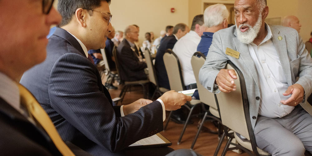 Mayor of Stockbridge Anthony Ford, right, hands off a business card to Federal Rail Administator Amit Bose before Bose spoke to the Interstate 75 Central Corridor Coalition in Indian Springs State Park. 