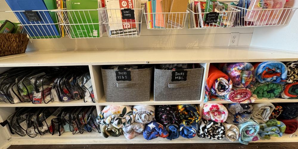 Socks, blankets, and toothbrush kits on the shelves of The Bloom Closet Express truck. 