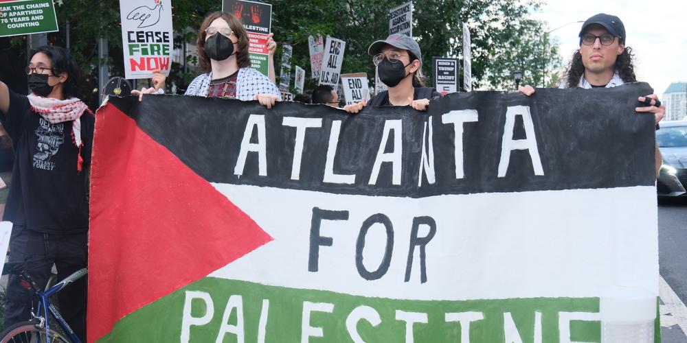 Three protesters hold a sign that says "Atlanta for Palestine" in Midtown on June 27, 2024.