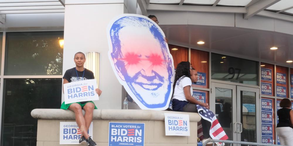 Joe Biden supporters sit amidst campaign signage, awaiting the president's arrival to the first presidential debate of 2024 in Atlanta on June 27. 