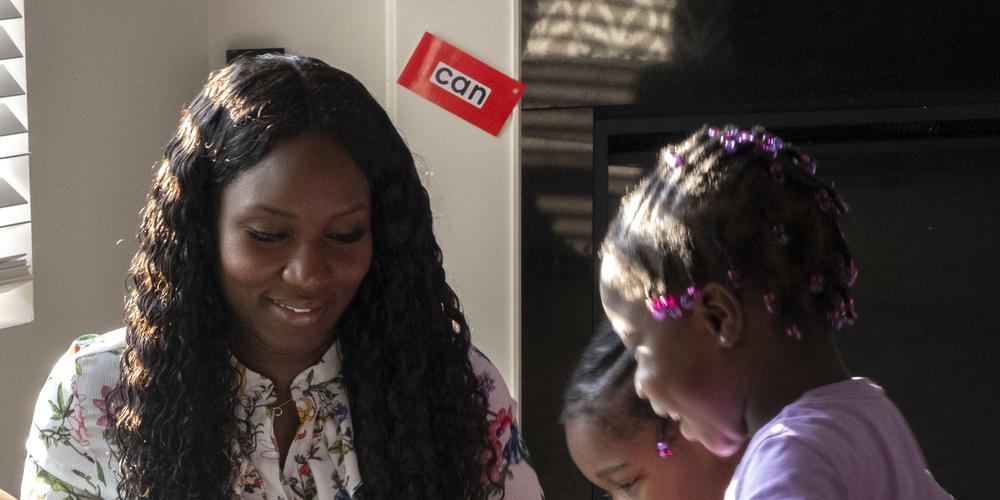 Emmanuella Altidor sits to play with her twin daughters at home.