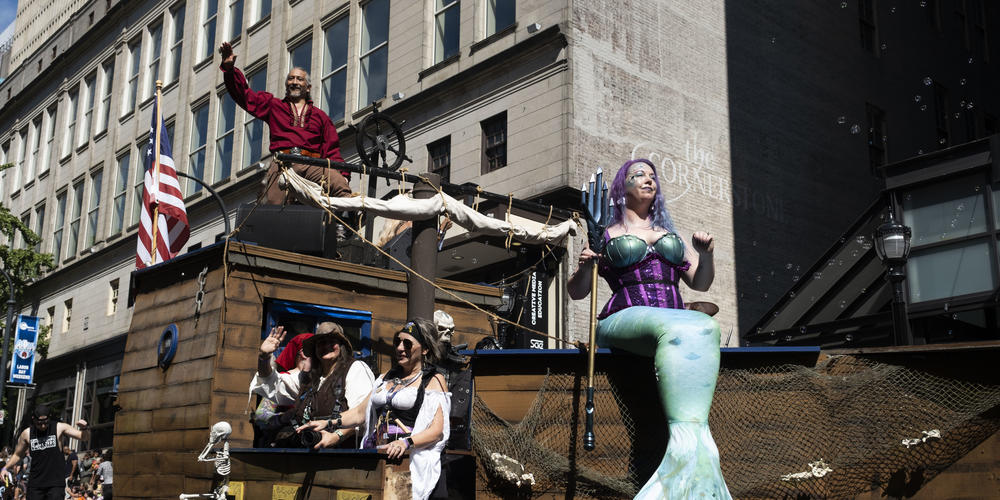 Pirate cosplayers ride through the parade on a boat float at Dragon Con 2024.