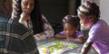 Emmanuella, Justice and Journey play a board game together at home.